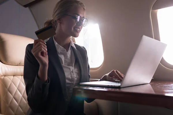 Geschäftsfrau arbeitet während Geschäftsreise mit Kreditkarte und Laptop im Flugzeug — Stockfoto