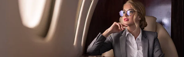 Líder de negócios atraente sentado no avião durante a viagem de negócios — Fotografia de Stock