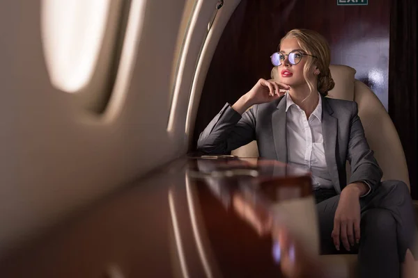 Femme d'affaires professionnelle dans des lunettes assis dans l'avion pendant le voyage d'affaires — Photo de stock