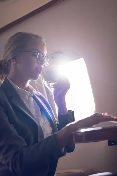 Приваблива бізнес-леді п'є каву в літаку під час ділової поїздки — стокове фото