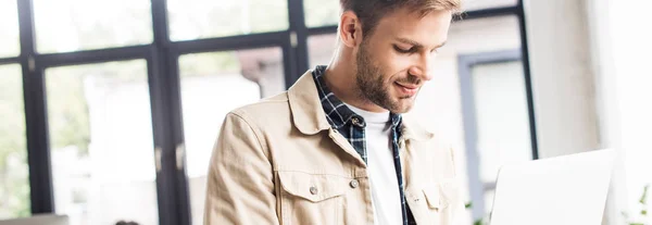 Plano panorámico de joven hombre de negocios utilizando portátil en la oficina - foto de stock