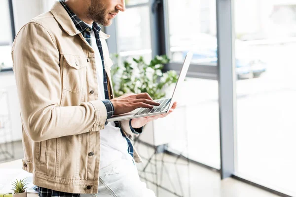 Vue recadrée de jeune homme d'affaires en utilisant un ordinateur portable dans le bureau — Photo de stock