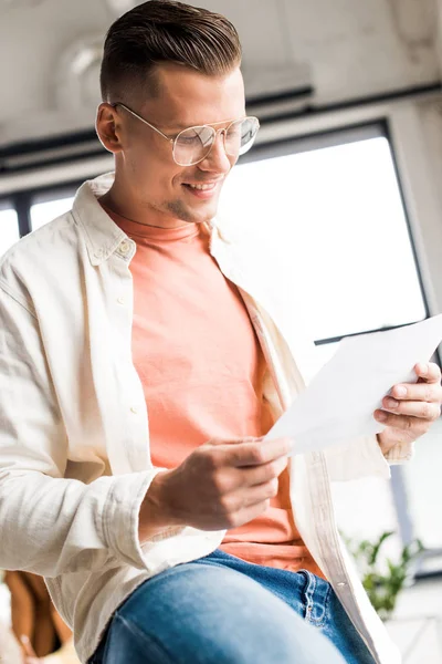 Gutaussehender, junger Geschäftsmann schaut im Büro auf Papier — Stockfoto