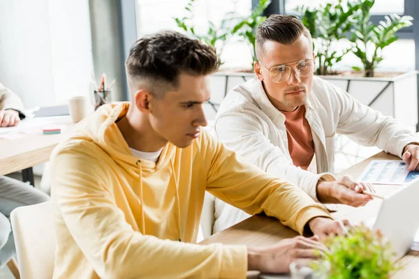 Zwei junge Geschäftsleute sitzen am Arbeitsplatz und arbeiten zusammen im Büro — Stockfoto