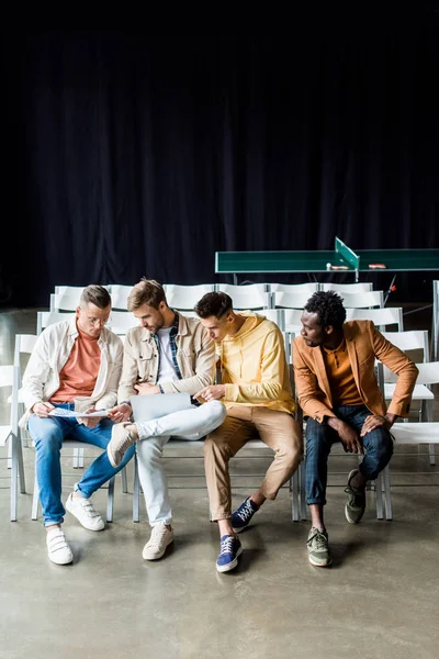 Quatro jovens empresários multiculturais discutindo o projeto de startup enquanto estão sentados na sala de conferências — Fotografia de Stock