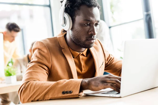 Handsome african american businessman in headphones using laptop — Stock Photo