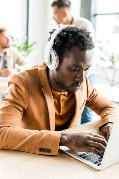 Young, handsome african american businessman in headphones using laptop — Stock Photo