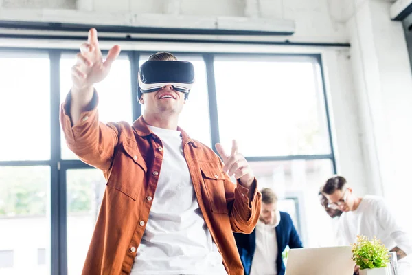 Young businessman using vr headset while multicultural colleagues working in office — Stock Photo