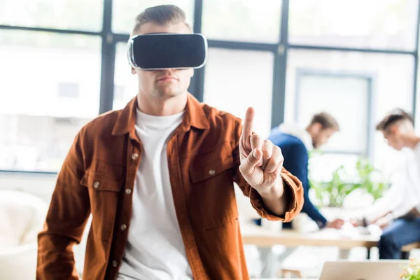 Junger Geschäftsmann berührt etwas mit dem Finger, während er Virtual-Reality-Headset im Büro benutzt — Stockfoto