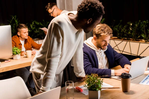 Young multicultural colleagues working on startup project at night in office — Stock Photo