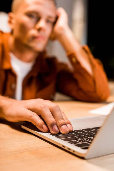 Foco seletivo do empresário exausto usando laptop à noite no escritório — Fotografia de Stock