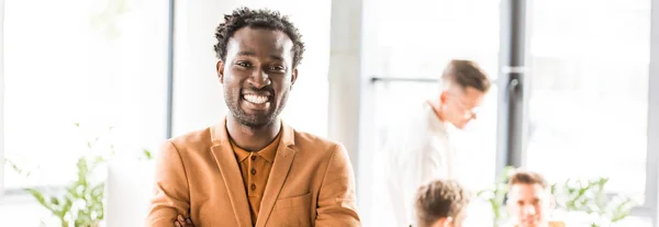 Tiro panorâmico de jovem empresário afro-americano sorrindo para a câmera — Fotografia de Stock