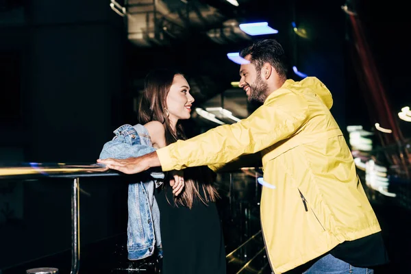 Seitenansicht eines lächelnden Freundes und einer Freundin, die sich in der nächtlichen Stadt anschauen — Stockfoto