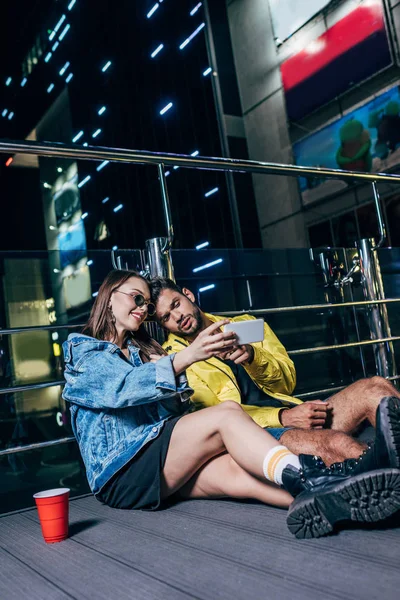 Guapo novio y atractiva novia sonriendo y tomando selfie en la noche de la ciudad - foto de stock