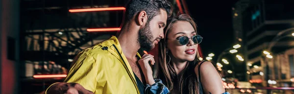 Panoramic shot of handsome boyfriend and attractive girlfriend hugging in night city — Stock Photo