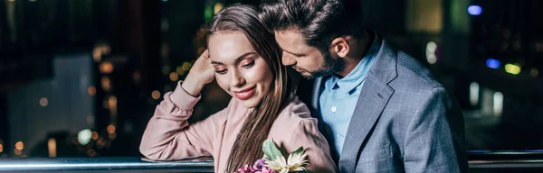 Panoramic shot of handsome businessman hugging attractive woman in night city — Stock Photo