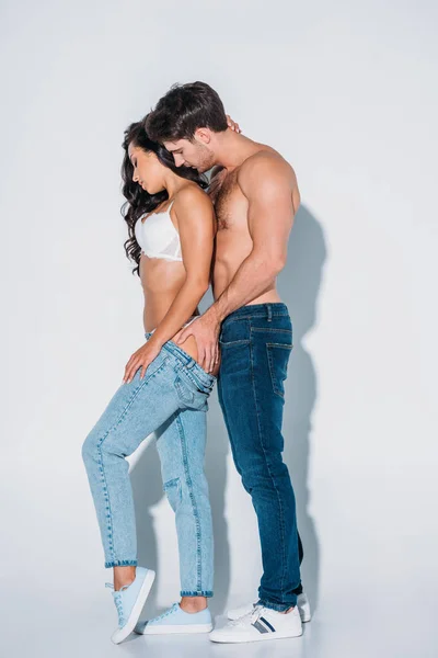 Sexy joven tocando nalgas de novia en gris fondo - foto de stock