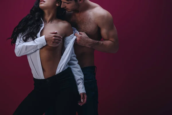 Partial view of shirtless man undressing sexy girl in unbuttoned white shirt on dark background — Stock Photo