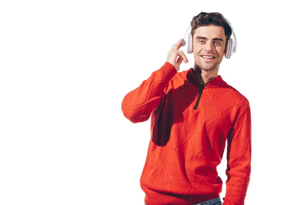 Hombre sonriente en suéter rojo escuchando música con auriculares, aislado en blanco - foto de stock