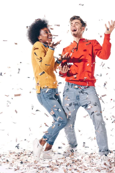 Feliz pareja multiétnica bailando con confeti, aislado en blanco - foto de stock