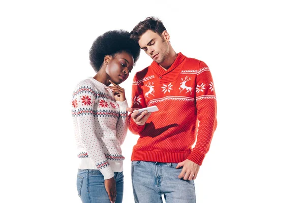 Hermosa pareja interracial pensativo usando teléfono inteligente, aislado en blanco - foto de stock