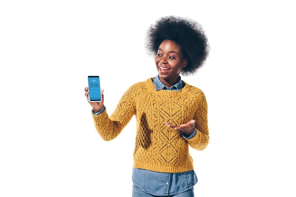 KYIV, UKRAINE - 21 AOÛT 2019 : fille afro-américaine montrant un smartphone avec application skype à l'écran, isolée sur blanc — Photo de stock
