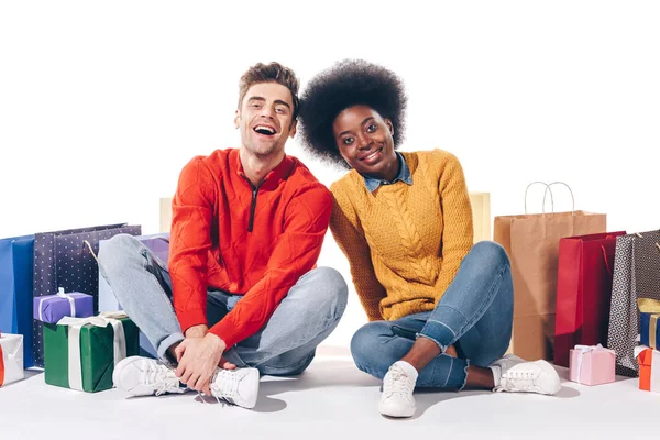 Heureux couple interracial avec des sacs à provisions et des cadeaux, isolé sur blanc — Photo de stock