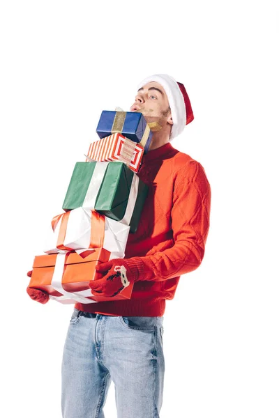 Красивий чоловік у капелюсі Санта тримає стек різдвяних подарунків, ізольований на білому — стокове фото