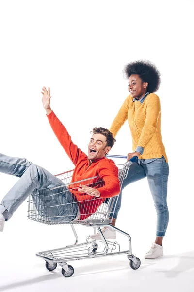 Multikulturelles Paar hat Spaß am Einkaufswagen, isoliert auf weiß — Stockfoto