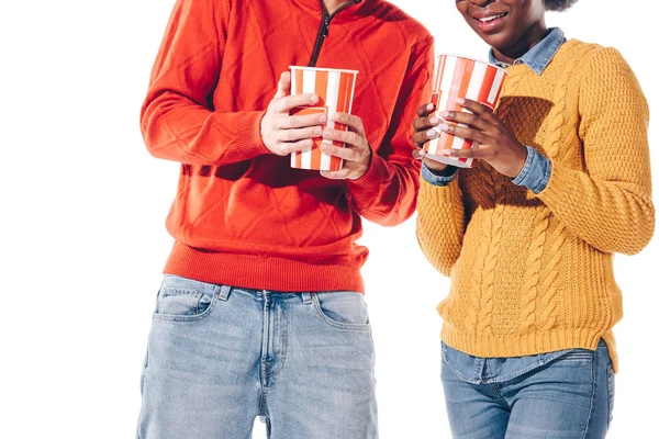 Vista recortada de pareja multicultural sosteniendo palomitas de maíz, aislado en blanco - foto de stock