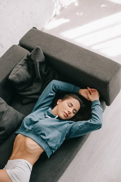 Beautiful woman in white panties lying on sofa with closed eyes — Stock Photo