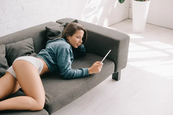 Attraktive sexy Frau in Höschen mit digitalem Tablet auf dem Sofa — Stockfoto