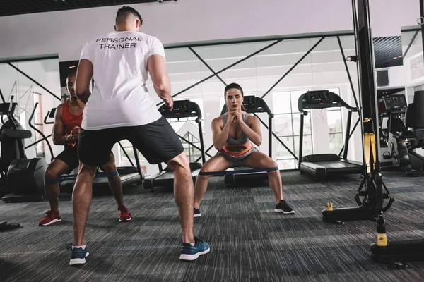 Rückansicht des Personal Trainers, der neben multikulturellen Athleten steht, die sich im Fitnessstudio aufwärmen — Stockfoto