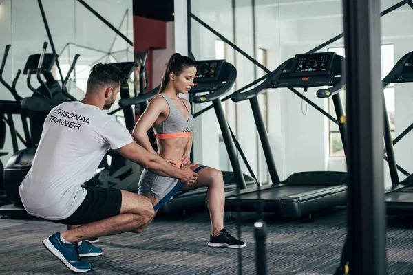 Entraîneur personnel instruisant jeune sportive faisant de l'exercice avec bande de résistance — Photo de stock