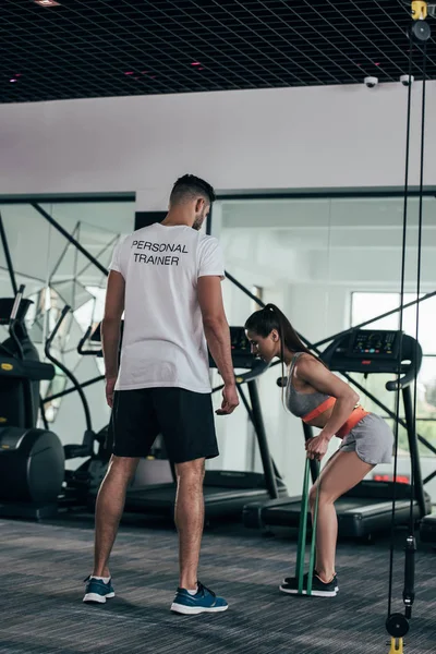 Visão traseira do personal trainer olhando atleta esportista exercitando com bandas de resistência — Fotografia de Stock