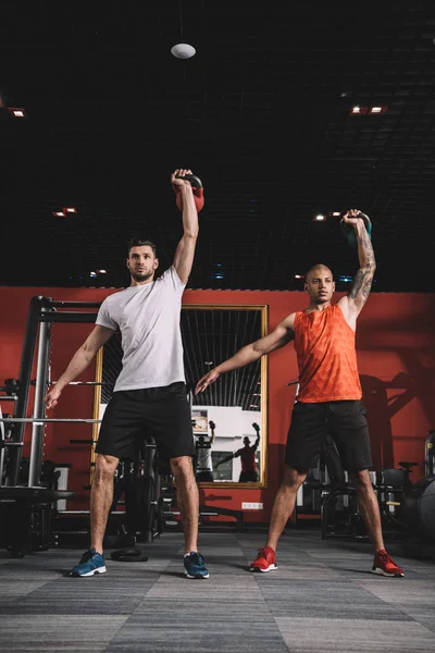 Handsome trainer lifting weight together with african american athlele — Stock Photo