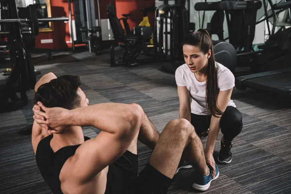 Attraktive Trainerin unterstützt gutaussehenden Sportler bei Liegestützen — Stockfoto