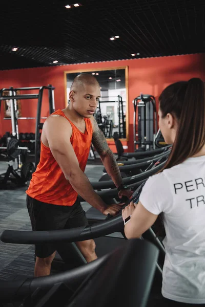 Personal Trainer steht neben afrikanisch-amerikanischem Sportler auf Laufband — Stockfoto