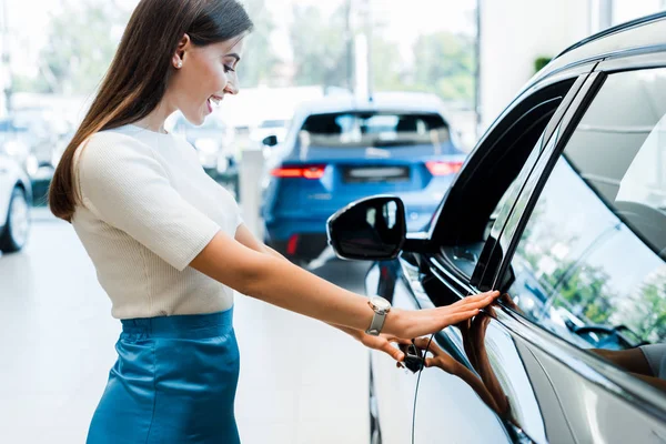 Seitenansicht einer aufgeregten jungen Frau beim Anblick eines schwarzen Autos — Stockfoto