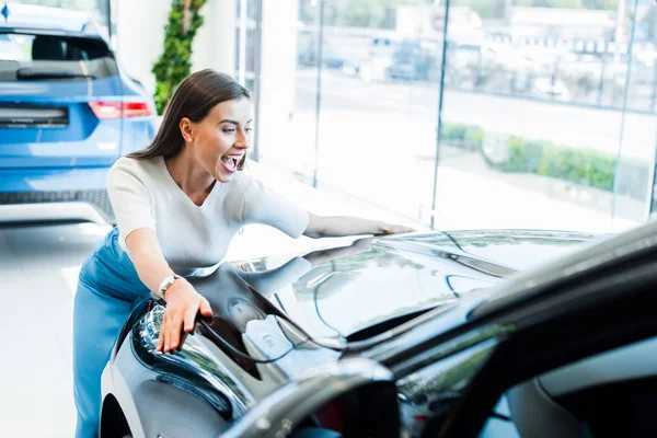 Selective focus of excited woman touching black car — Stock Photo