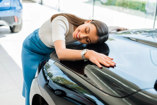 Selektiver Fokus einer glücklichen Frau mit geschlossenen Augen in der Nähe eines schwarzen Autos — Stockfoto