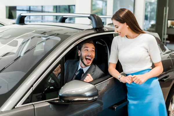 Attractive woman standing near excited man in car — Stock Photo