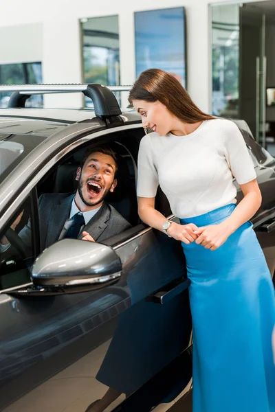 Young and attractive woman standing near excited man in car — Stock Photo