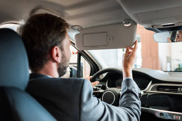 Messa a fuoco selettiva di uomo barbuto seduto in auto e tenendo volante — Foto stock