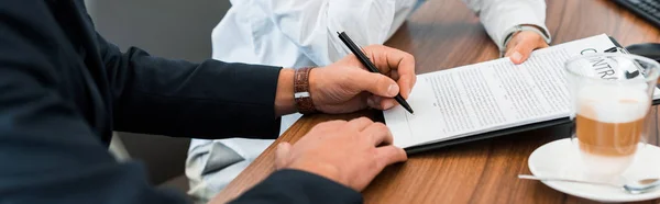 Panoramic shot of car dealer holding clipboard near man with pen — Stock Photo