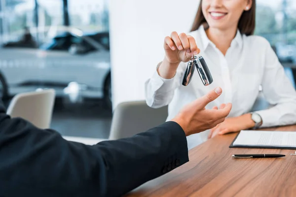 Ausgeschnittener Blick auf glücklichen Autohändler, der Mann Autoschlüssel gibt — Stockfoto