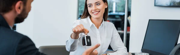 Plano panorámico del distribuidor alegre del coche que da la llave del coche al hombre - foto de stock