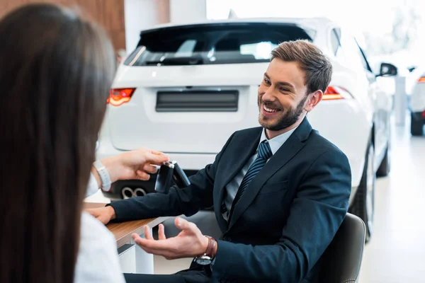 Rückseite des Autohändlers gibt Autoschlüssel an glücklichen bärtigen Mann — Stockfoto