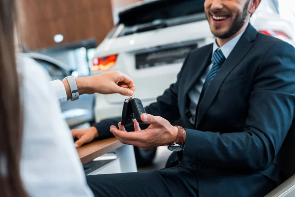 Cropped view of car dealer giving car keys to happy bearded man — Stock Photo