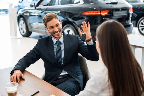 Selektiver Fokus eines glücklichen bärtigen Autohändlers mit Autoschlüssel in der Nähe einer Frau — Stockfoto